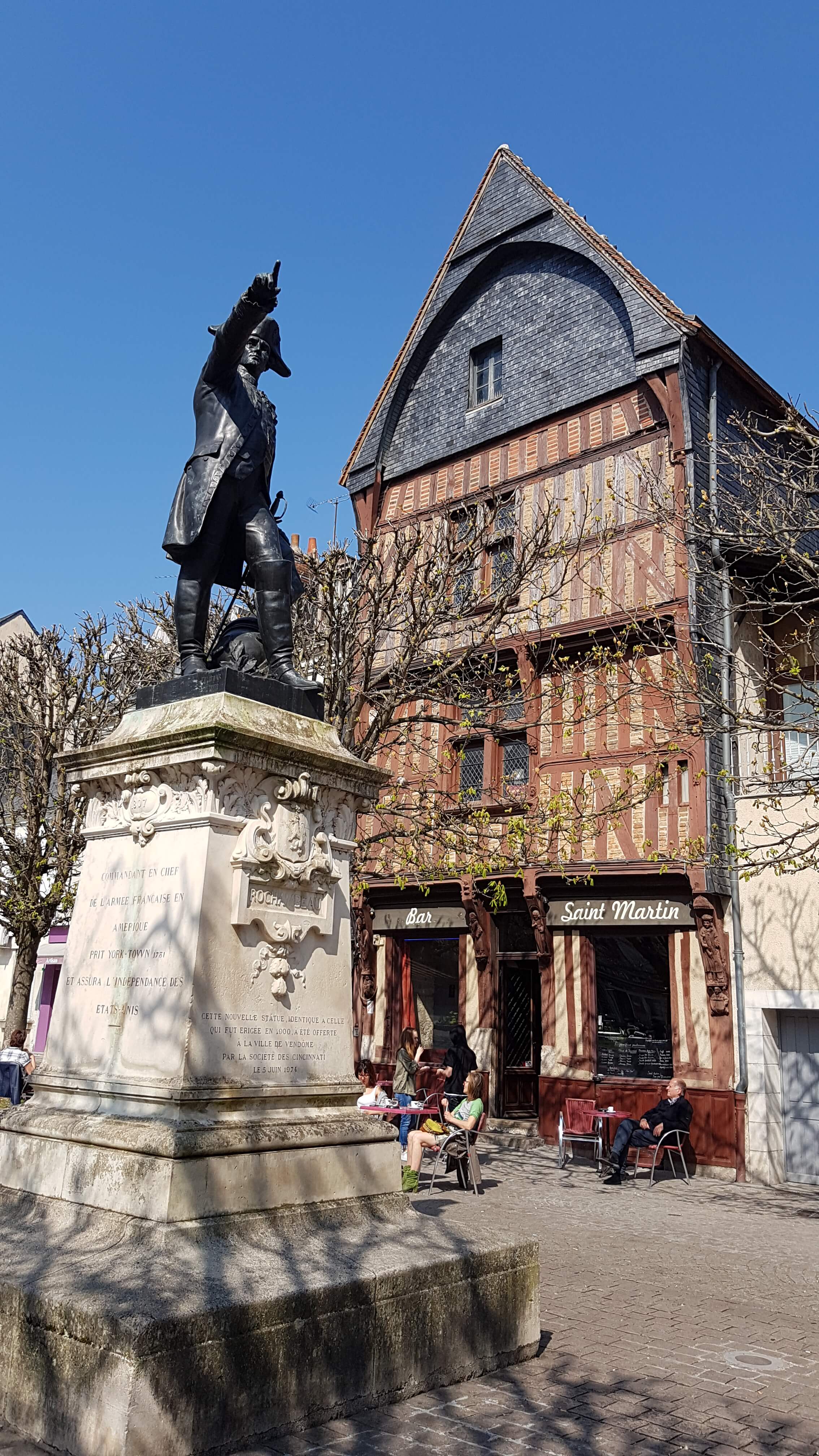 En premier plan la statue du Maréchal de Rochambeau et derrière lui une maison à pans de bois